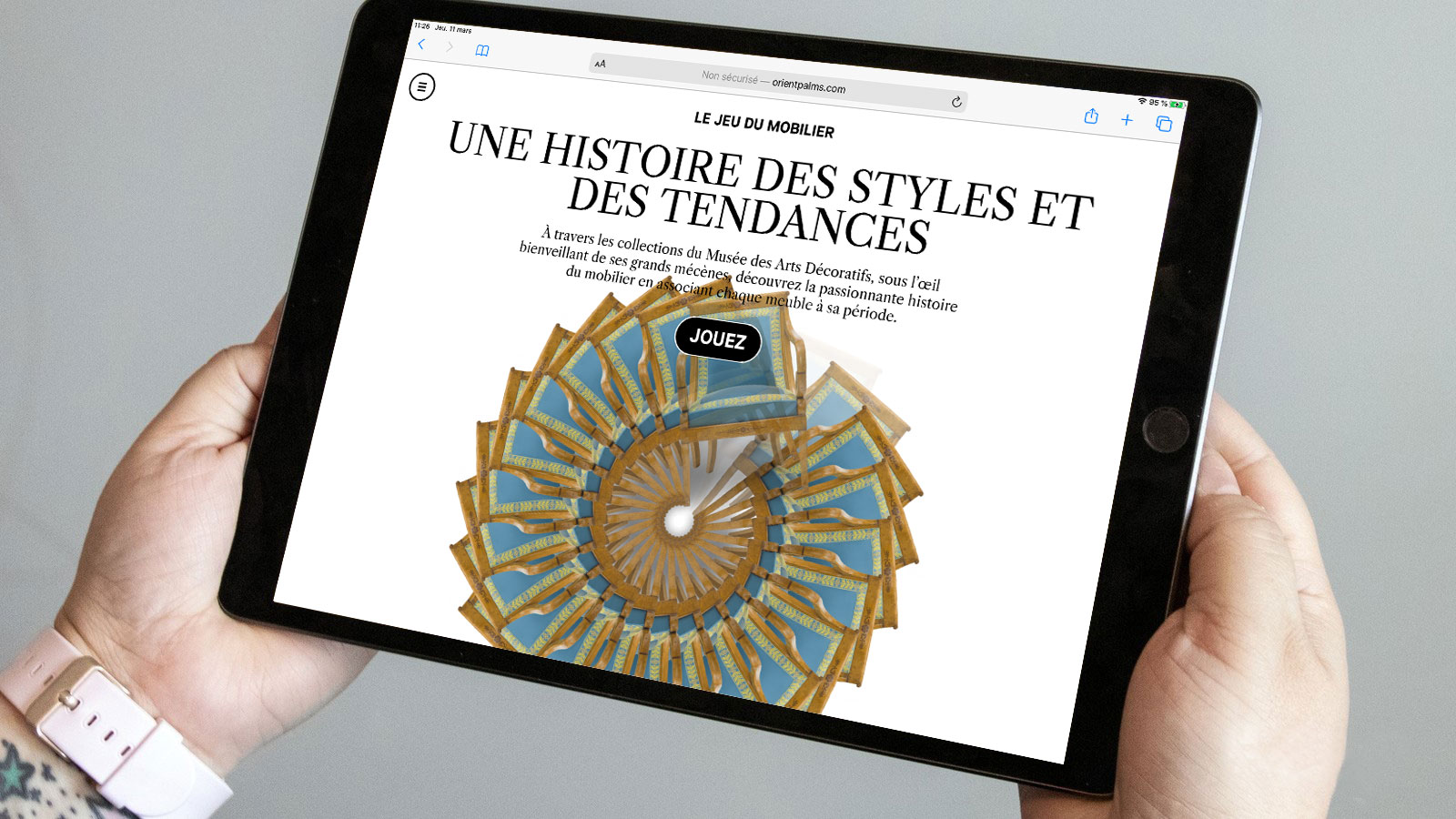 L'image montre une personne tenant une tablette, sur laquelle s'affiche une page web intitulée "Une histoire des styles et des tendances". Le design présente un motif circulaire orné de formes et de couleurs, suggérant un lien avec le mobilier ou l'art décoratif. Un bouton "Jouez" est visible, invitant les utilisateurs à interagir avec le contenu.