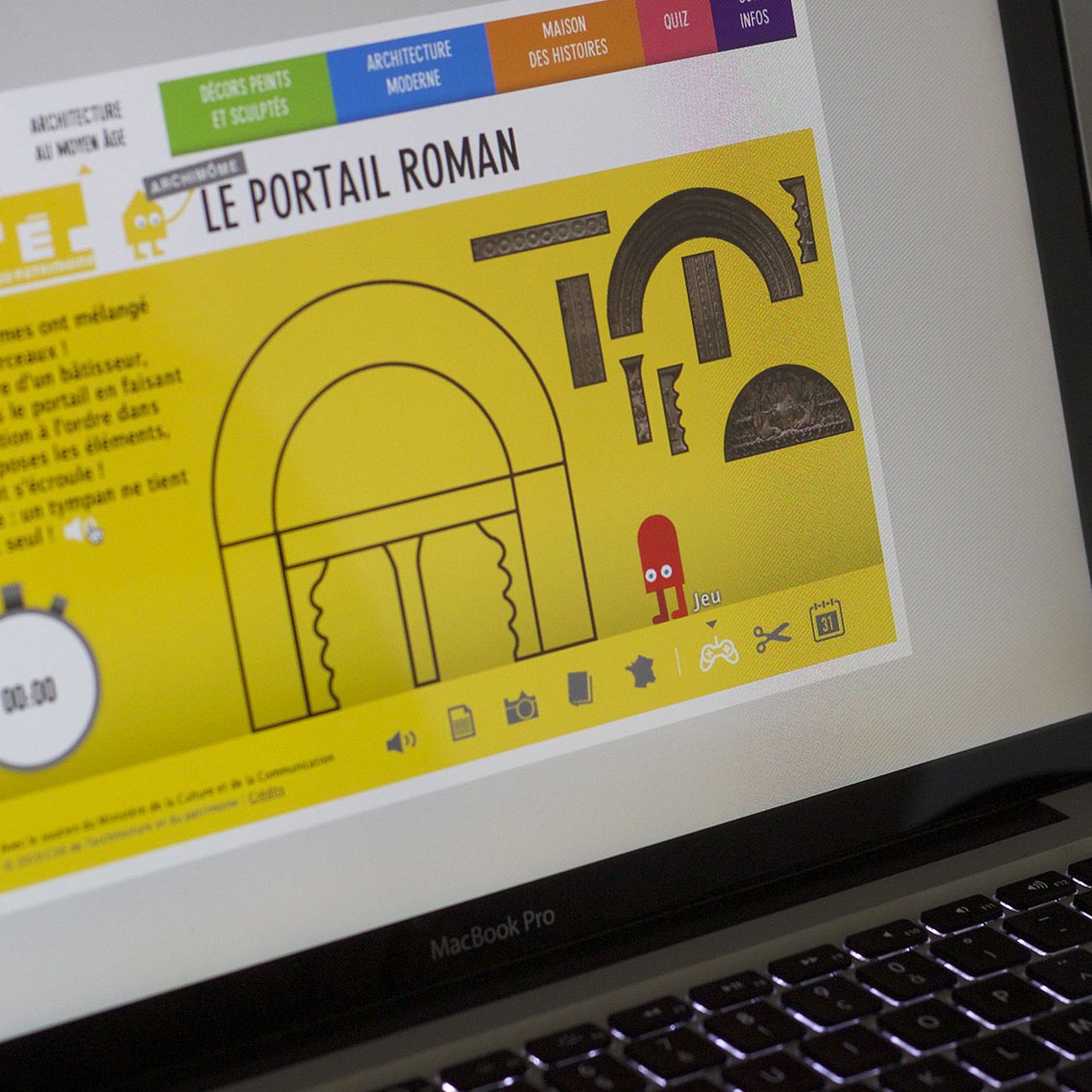 L'image montre une personne utilisant un ordinateur portable, probablement un MacBook. L'écran affiche une interface colorée, centrée sur un thème d'architecture romane. On peut y voir un grand arc, des motifs géométriques et des éléments graphiques sur fond jaune. Un chronomètre est visible, indiquant un compte à rebours de 00:00. Cela semble être une leçon ou une activité interactive sur les caractéristiques de l'architecture romane.